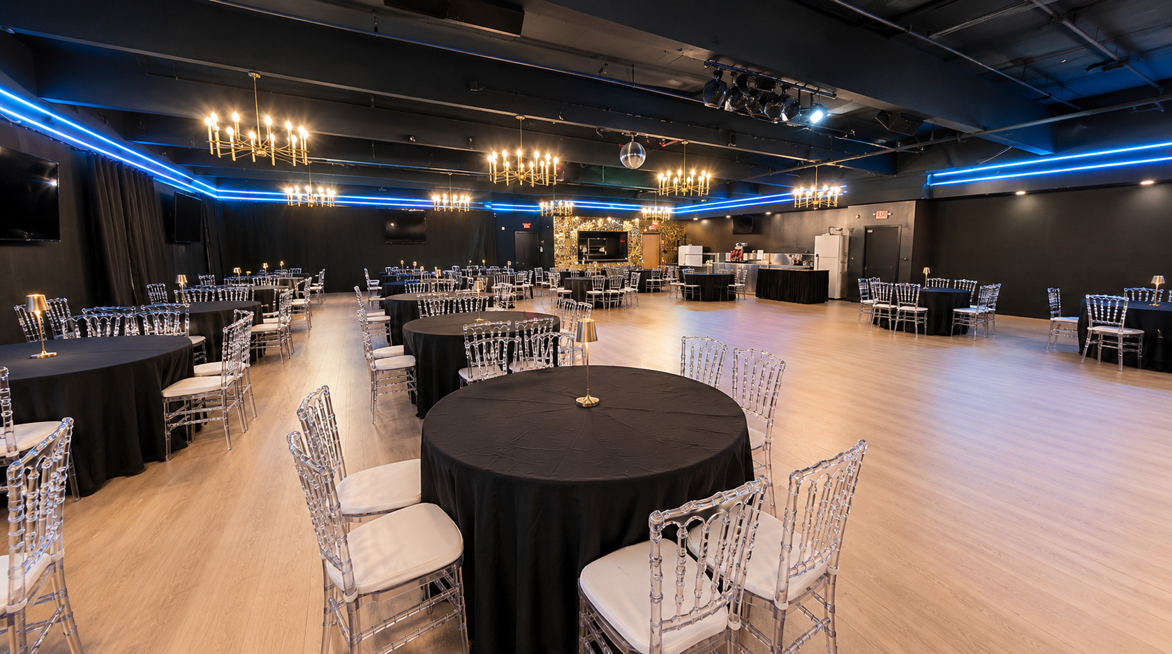 The grand hall set with round banquet tables and a lit stage